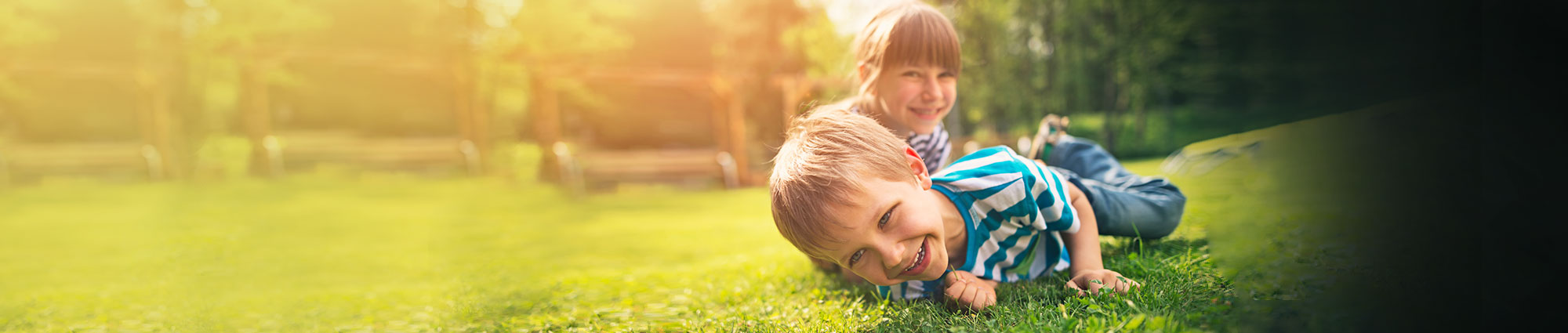 Two children laying in the grass smiling for a picture.